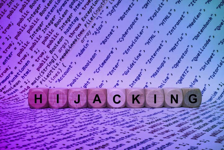 Image of the word hijacking in scrabble like letters with coding scripts behind it 